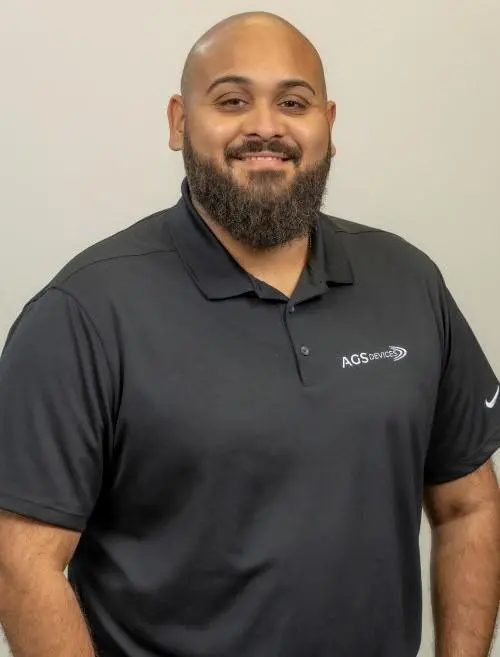 Jermaine Negroni, Operations Manager at AGS Devices, wearing a branded black AGS Devices t-shirt in a profile.