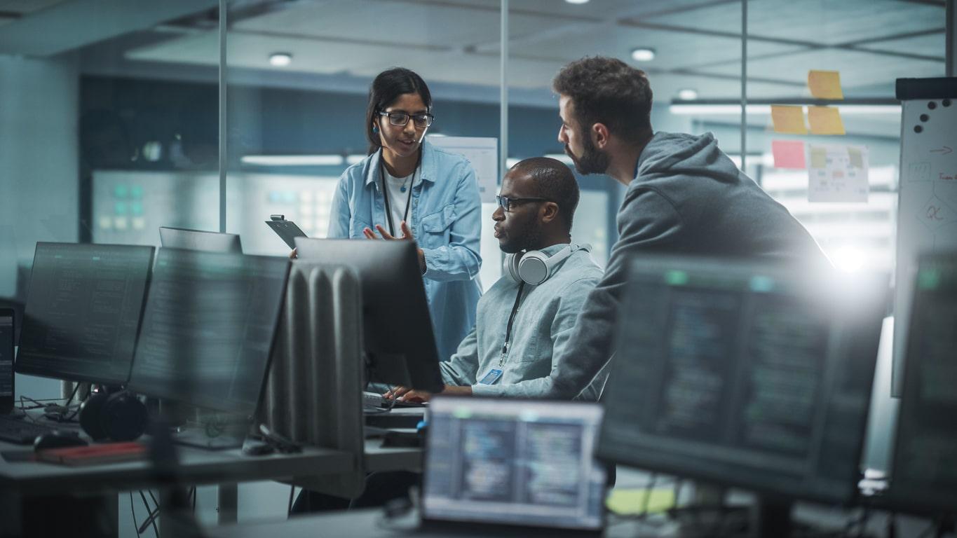 Diverse Group of Professionals Meeting in Modern Office: IT Programmers Use Computer, Talk Strategy, Discuss Planning. Specialists Create Innovative Software. Engineers Develop Inspirational App